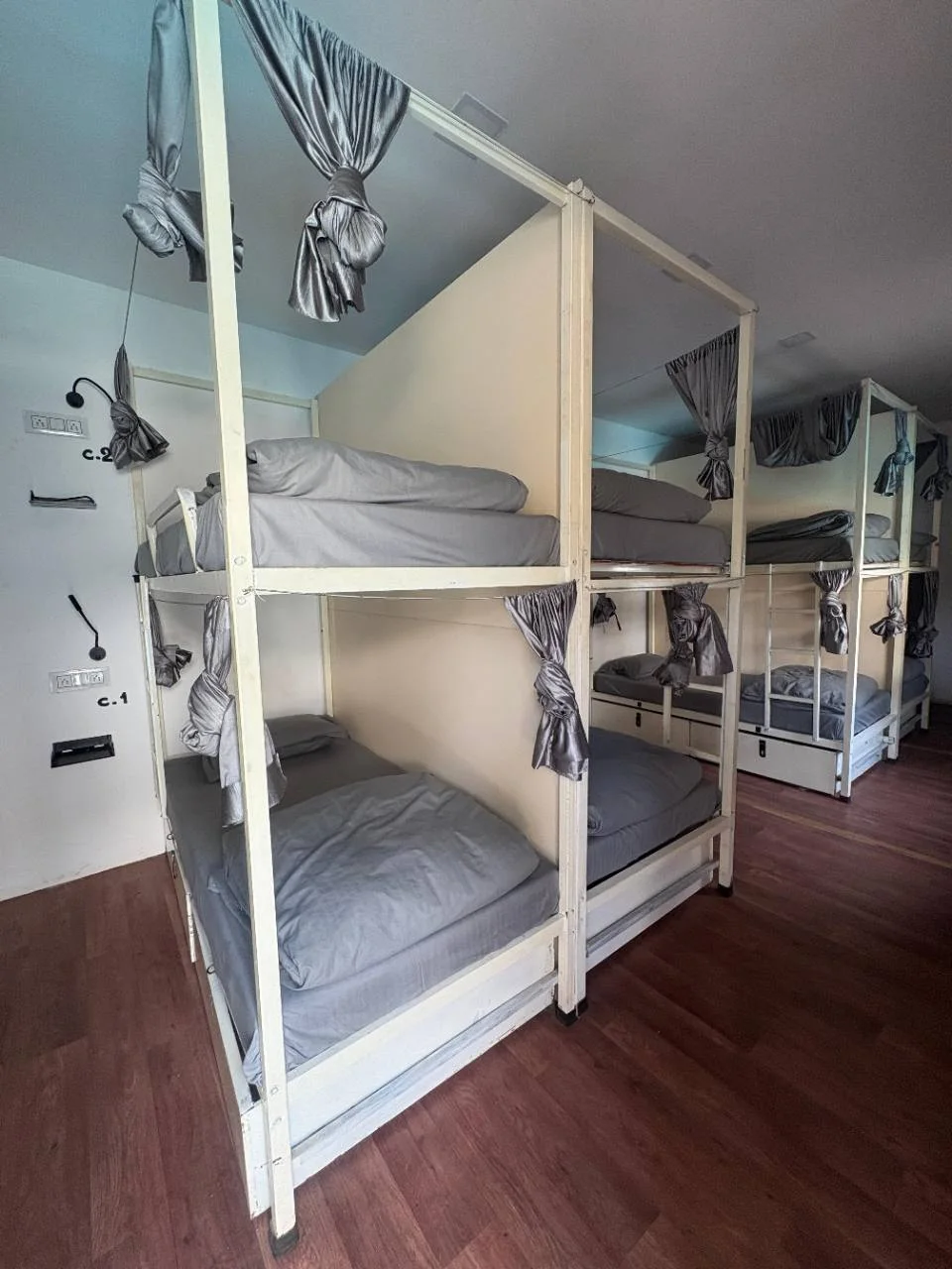 Eight-bed dormitory interior with curtained bunk beds at Half Orange in Vagator