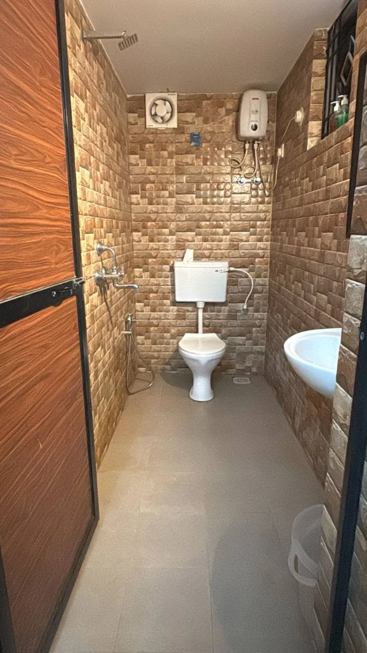Attached bathroom with shower, basin and geyser in a Deluxe Room at Half Orange
